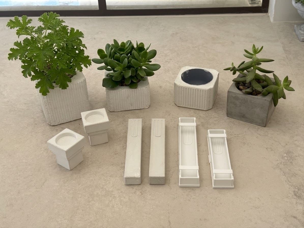 Finished concrete planters and mezuzah cases displayed with their 3D-printed molds