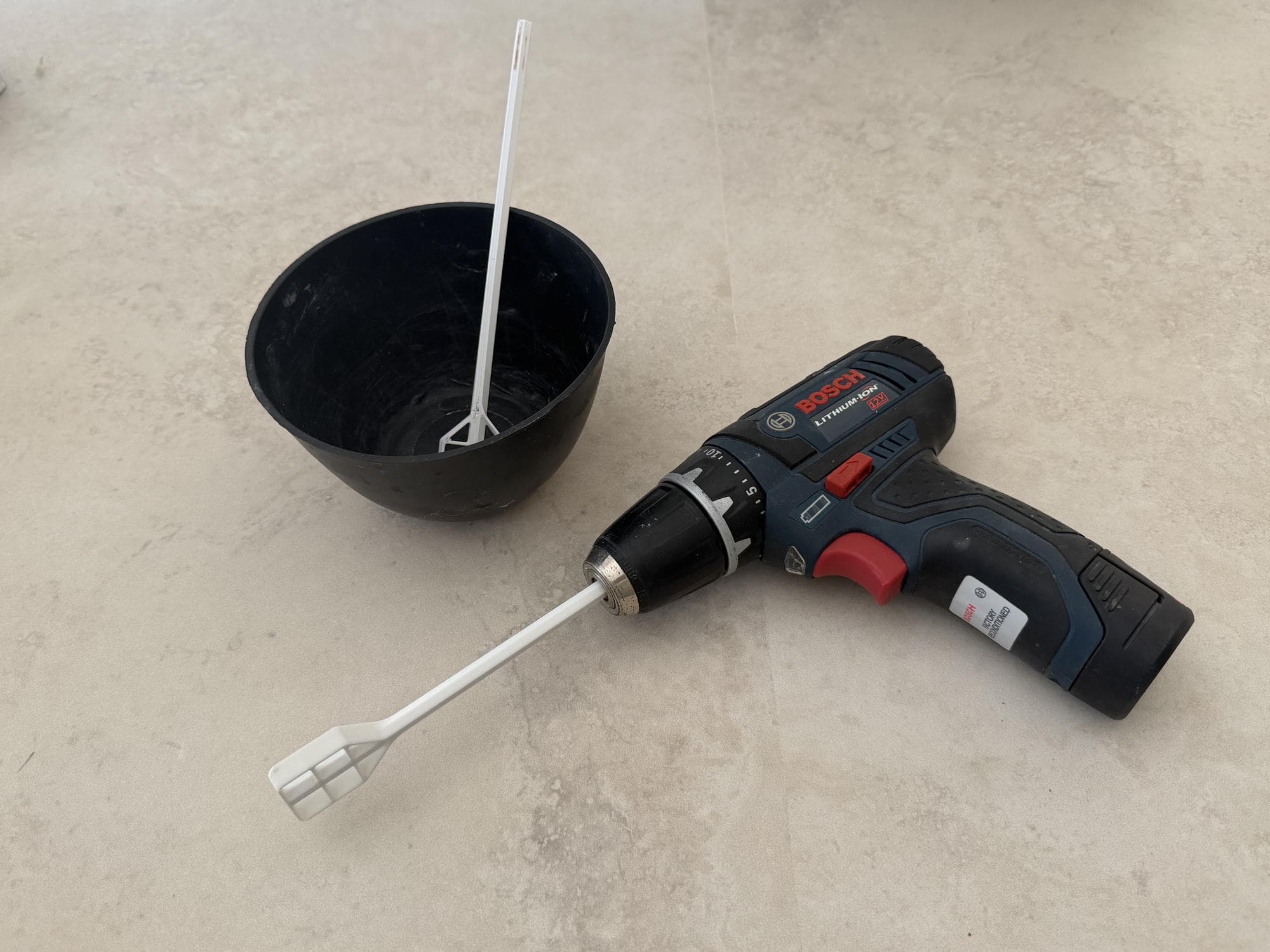 Bosch cordless drill fitted with a white 3D-printed concrete mixing paddle beside a mixing bowl